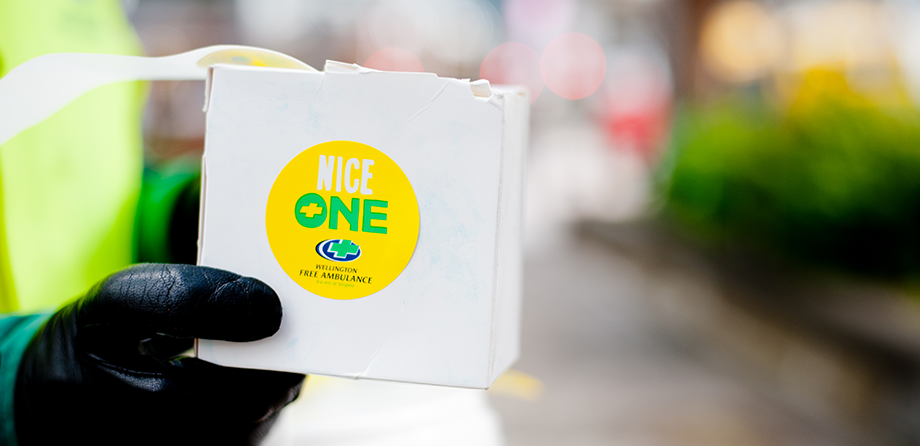Street Collector holding out a box of stickers that say Nice One