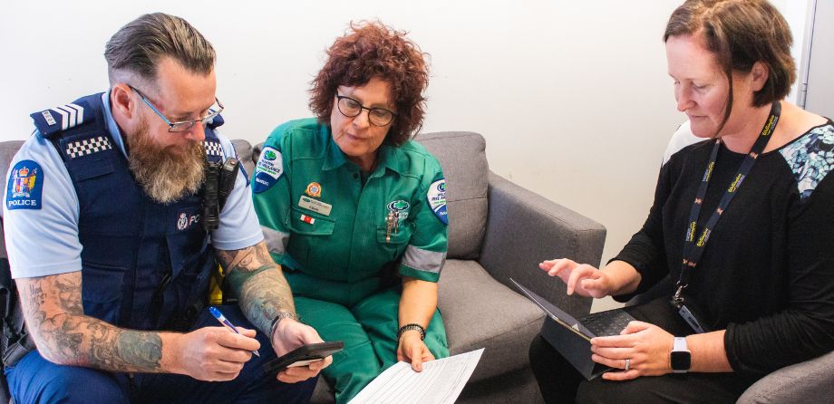 A police officer, paramedic and healthcare worker chat on a sofa