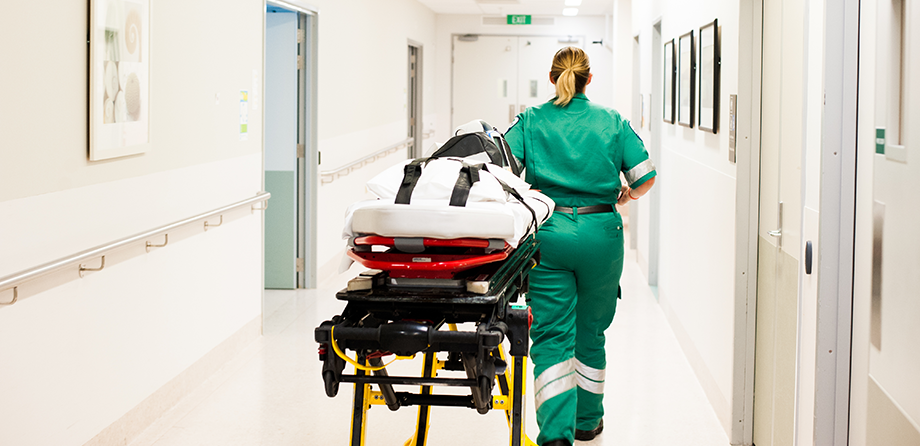 Paramedic walking down hallway with stretcher