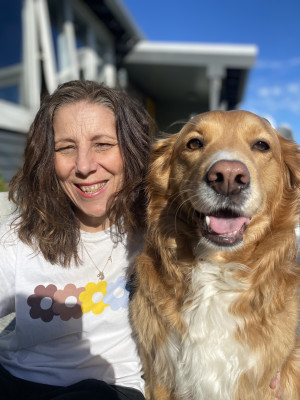 A woman smiles next to a golden haired dog