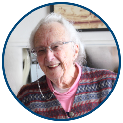 A woman with white hair and glasses laughs