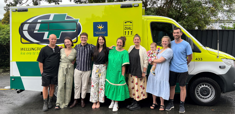 A group of people smile in front of an ambulance