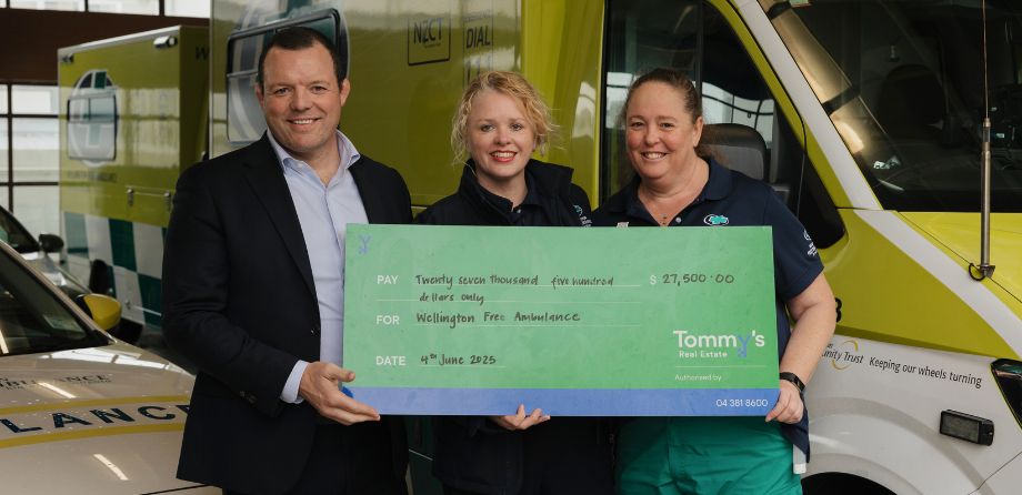 3 people smile while holding a large cheque
