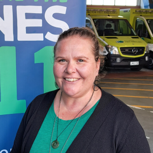 A woman stands in the Wellington Free Ambulance garage, with ambulances behind