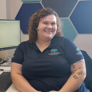 A woman in a blue Wellington Free polo shirt sits in front of a computer