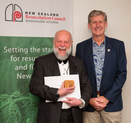2 men stand in front of a New Zealand Rescucitation Council sign