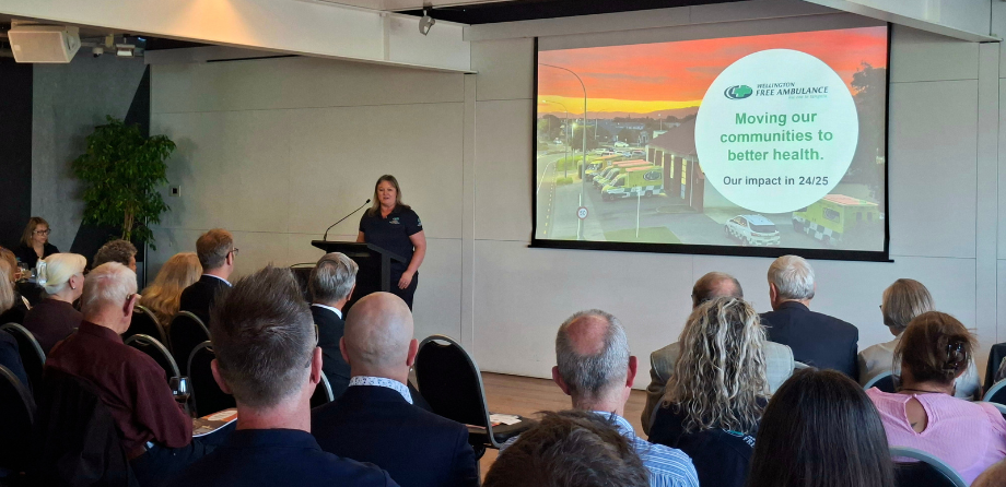 A woman stands at a lectern in front of an audience