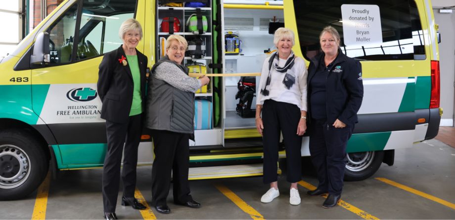 Four women stand in front of an ambulance