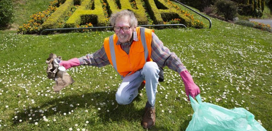 A man in a hi-vis vest holding a rubbish bag