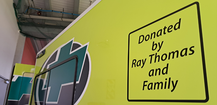 Close up of the side of an ambulance with text: donated by Ray Thomas and family