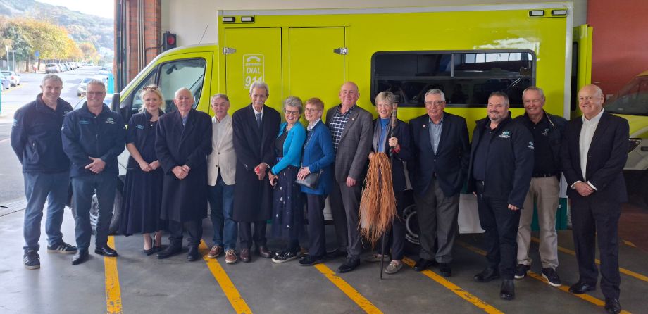 A group of people stand in front of an ambulance