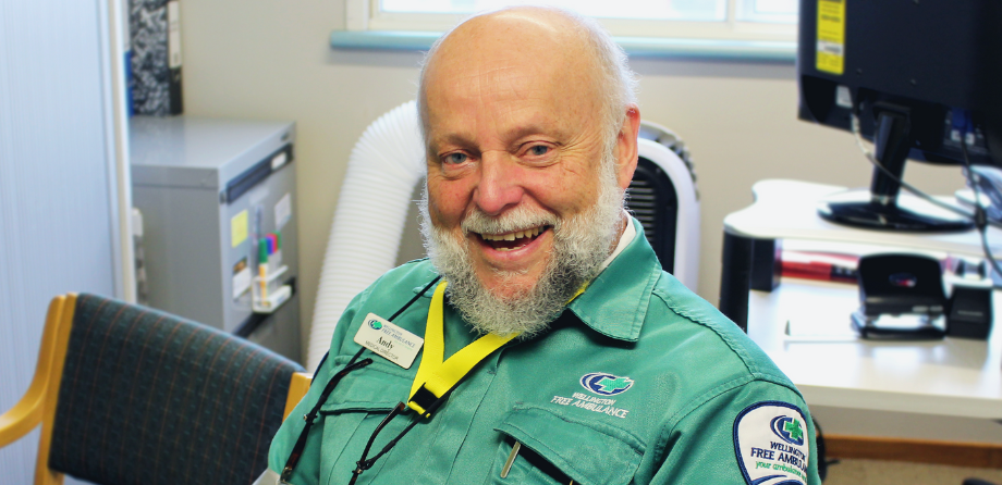 A man with a white beard and green uniform smiles