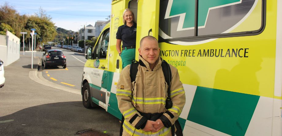 A firefighter smiles in front of an ambulance
