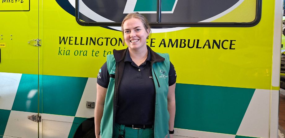 Patient transfer officer Monique smiles in front of an ambulance