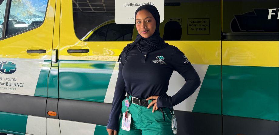 A paramedic smiles in front of an ambulance