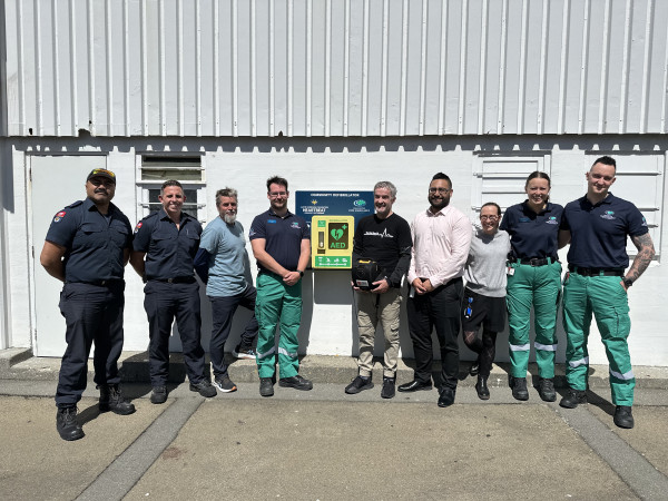A group of men and women stand around an AED on Wellington's waterfront