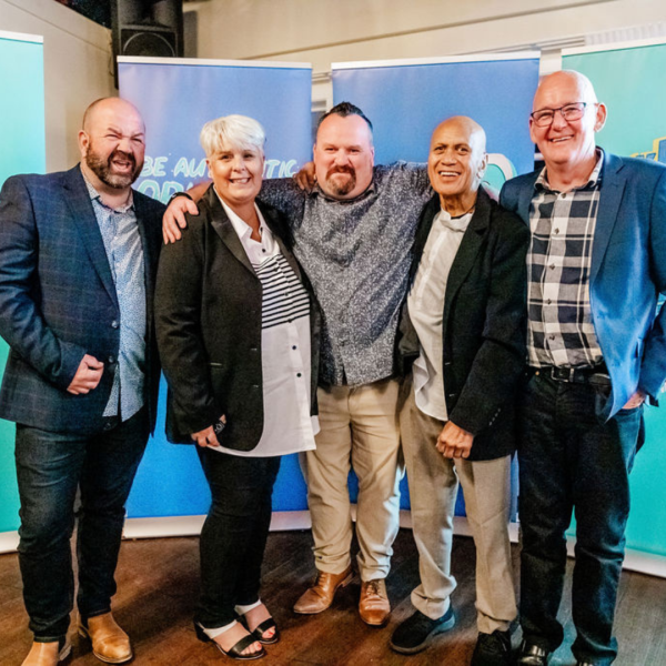 5 people with their arms around each other smile