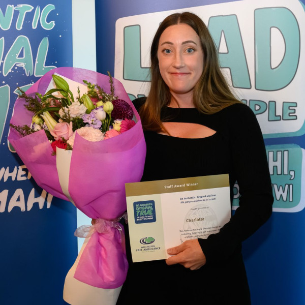 A woman holds a bouquet and certificate