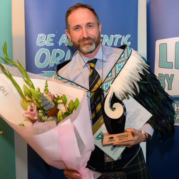 A man holds a bouquet, certificate and trophy