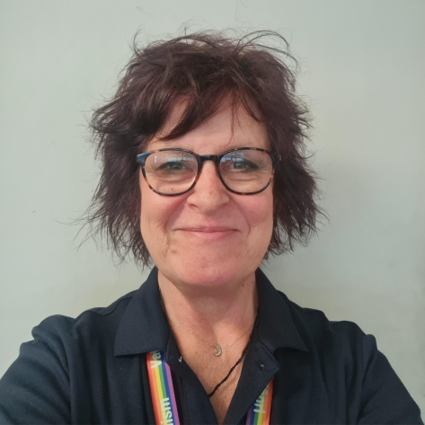 A close up of a woman with dark hair and glasses smiling