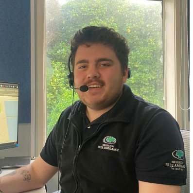 A man with short dark hair and a headset smiles