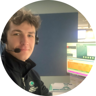 A call taker with a headset on smiles in front of a computer