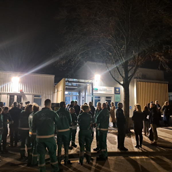 A group of paramedics stand in front of an ambulance station for a dawn blessing