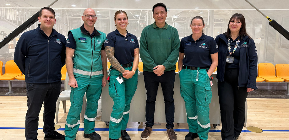 A group of paramedics, call takers and Kevin stand on a basketball court