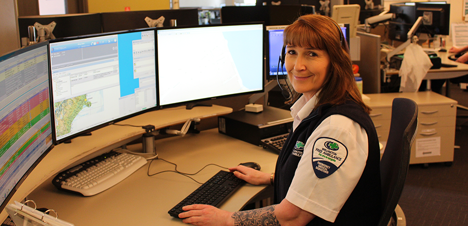 Emergency medical dispatcher sitting at desk smiling at camera