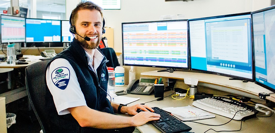 Emergency medical call taker sitting at desk smiling at camera