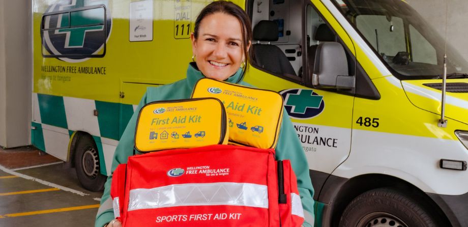 A paramedic holds three first aid kits