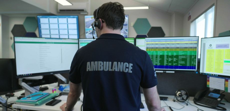 The back of a dispatcher in front of a row of screens