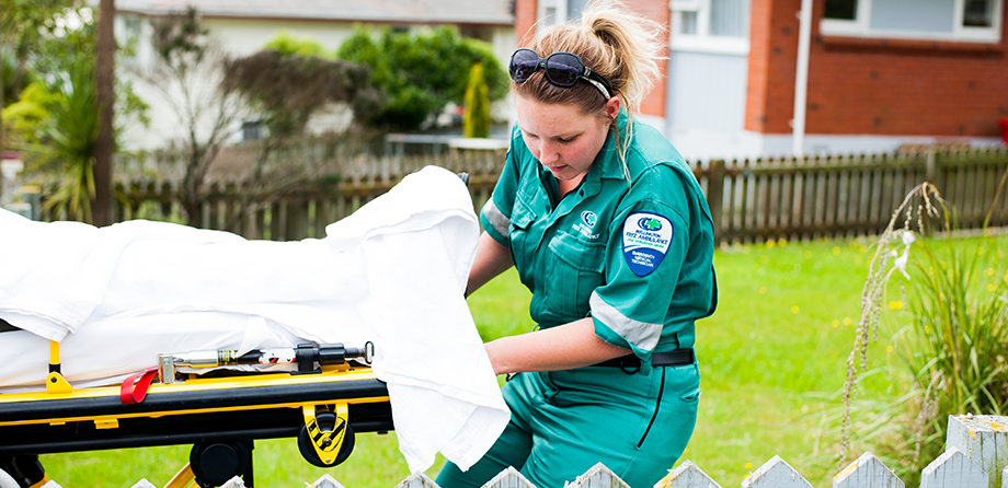 Patient transfer officer pulling stretcher near house