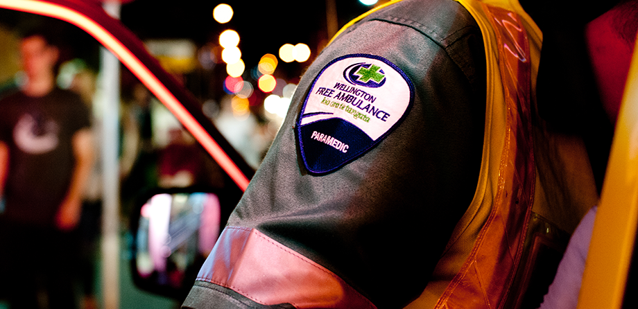 Paramedic leaning into a vehicle with a close up on their arm patch